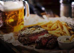 A mug of cold beer, a rare filet mignon, and french fries